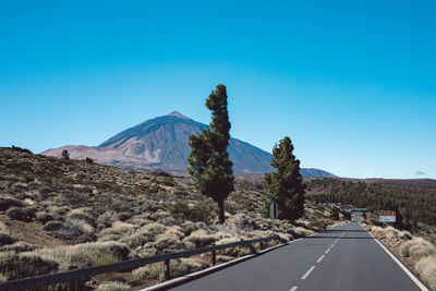 Road by mountains against clear blue sky