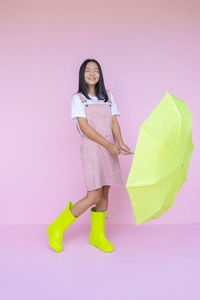 Full length portrait of woman standing against pink background