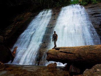 Man standing by waterfall
