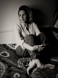 Young woman sitting on bed at home