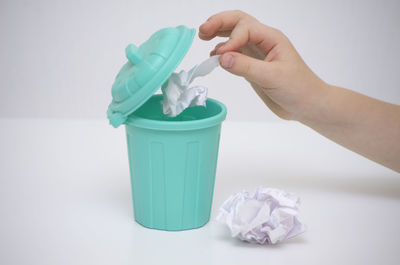 Close-up of hand holding paper against white background