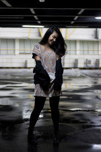 Full length of young woman standing on wet floor in parking lot
