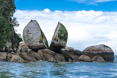 Rock formation by sea against sky