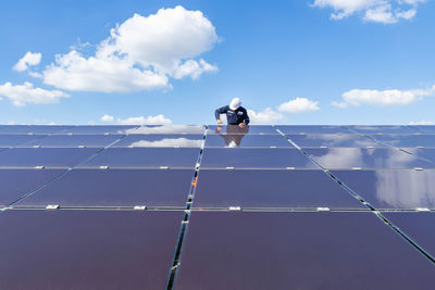 Low angle view of person paragliding on roof against sky