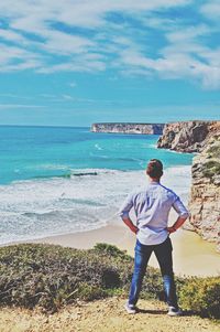 Rear view of man looking at sea against sky