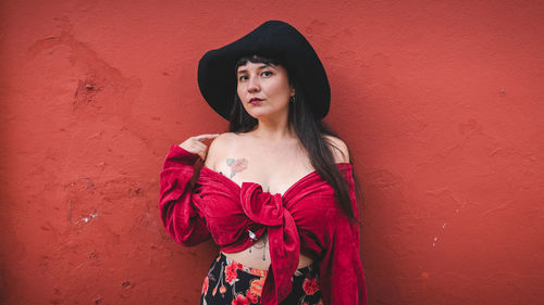 Dark-haired female model in vintage clothing and make-up against a colorful wall.