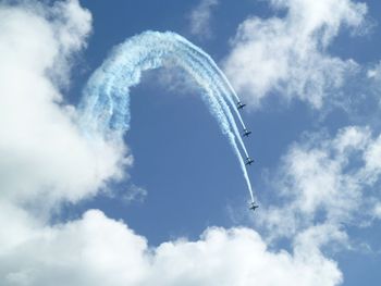 Low angle view of airplanes flying against cloudy sky