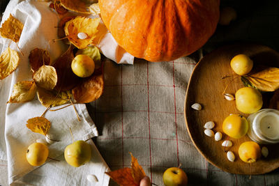 There is a layout of pumpkin and autumn leaves on the kitchen table