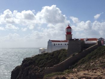 Lighthouse by sea against sky