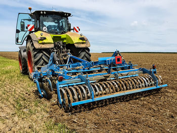 Tractor with disc harrow attached working the field