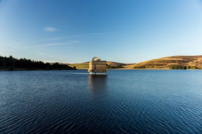 Scenic view of lake by building against blue sky