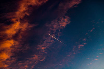 Low angle view of vapor trails against sky at sunset