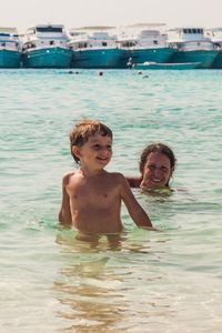 Smiling boy with mother swimming in sea