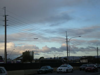 Cars on road against cloudy sky