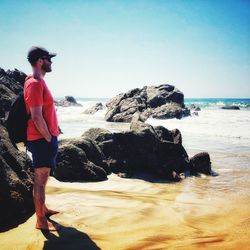 Full length of man on rock at beach against sky