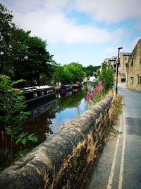 Canal amidst trees against sky in city