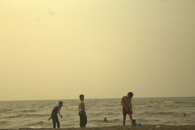 People on beach against clear sky