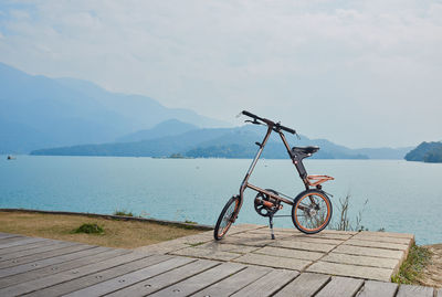 Bicycle by lake against sky