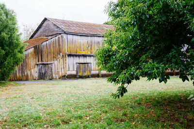 House and trees on field against sky