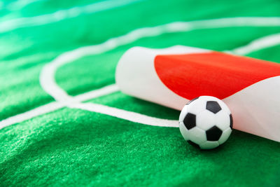 Close-up of small soccer ball with flag on green textile