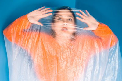 Woman covered in plastic standing against blue background