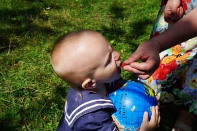 Cropped hand of mother feeding baby boy standing at back yard