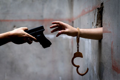Cropped hand giving gun to prisoner handcuffs in prison