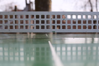 Close-up of railing with reflection on fence