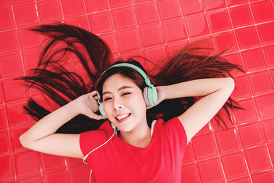 High angle portrait of young woman listening to music while lying on floor