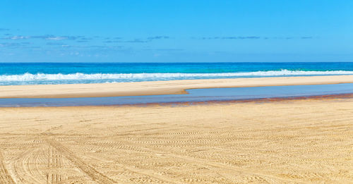 Scenic view of beach against blue sky