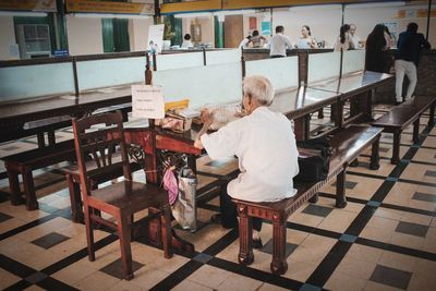 Rear view of woman sitting on table