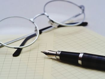 Close-up of pen and eyeglasses on papers