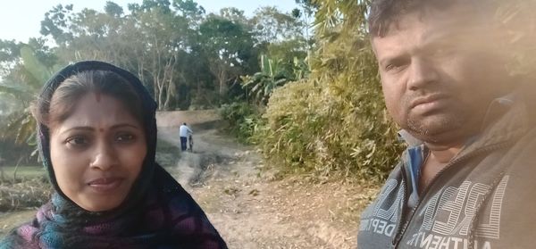 Portrait of young man with woman against trees