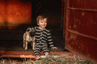 Baby boy toddler with a pug puppy sitting down