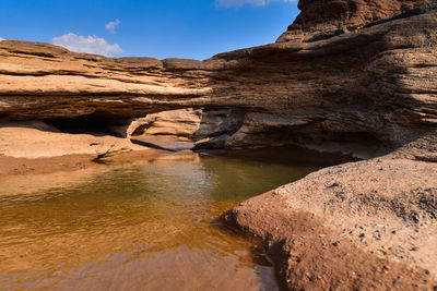 Pond in rock formations against sky