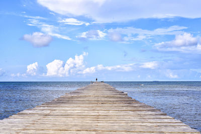 Empty jetty leading to calm blue sea