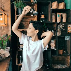 Smiling woman with hand raised standing at home