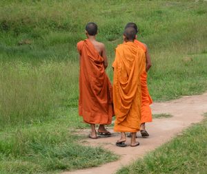 Rear view of monks standing on field