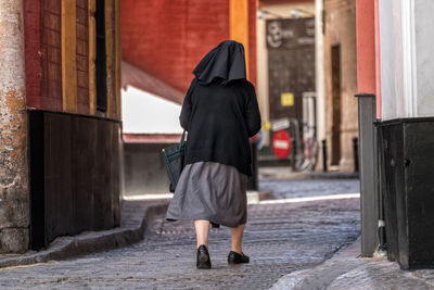 Rear view of nun walking on city street