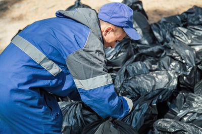 Rear view of man collecting garbage bags