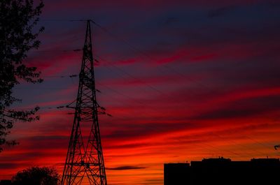 Low angle view of silhouette electricity pylon against dramatic sky