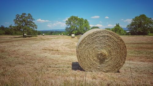 Hay bales on field against sky