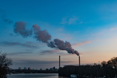 Smoke emitting from chimney against sky at sunset