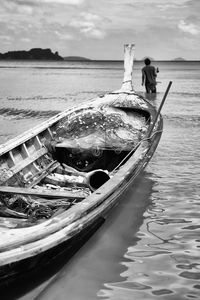 Close-up of fishing boat moored on lake with man in background