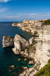 Rock formations by sea against blue sky