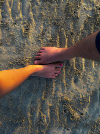 Low section of man and woman standing on sand at beach