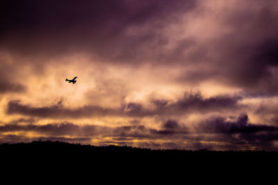 Low angle view of silhouette airplane against sky during sunset