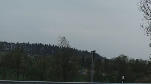 Trees on landscape against clear sky