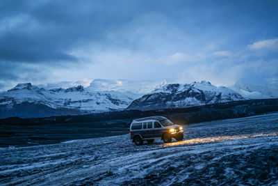 Car on snow covered mountain against sky