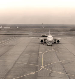 Airplane on airport runway against sky during sunset